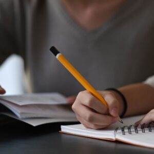 person writing with a pencil in a book