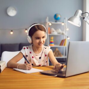 child with headphones on learning from a laptop